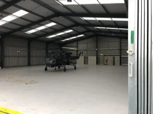 Open span helicopter hanger at Breighton Aerodrome, with helicopter inside