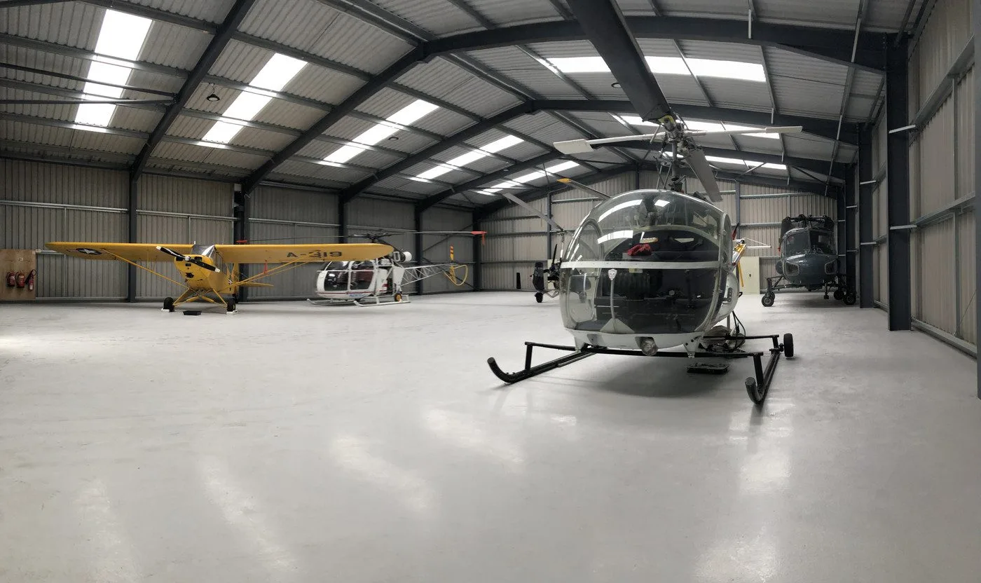 Helicopters and aeroplane docked inside a steel aircraft hangar