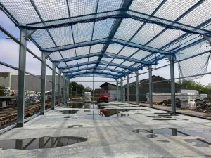 A steel framed building under construction, with a focus on health and safety measures including safety netting.