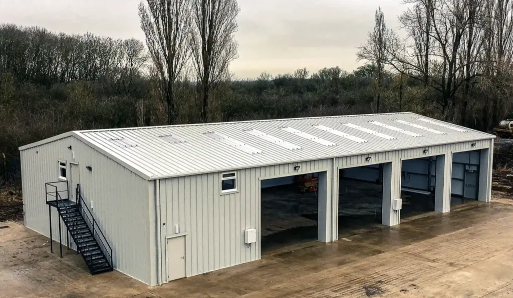 Large Steel building with 4 no. Open Roller Doors, and external stairs. Clad in white Kingspan Cladding