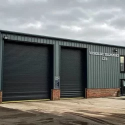 A steel-framed HGV workshop in Yorkshire, with several large bays for servicing and repairing heavy-duty vehicles, and a modern office space visible in the background.