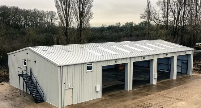 Large Steel building with 4 no. Open Roller Doors, and external stairs. Clad in white Kingspan Cladding